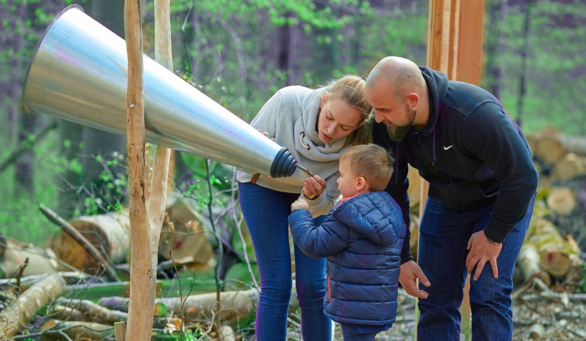 Eine Familie mit einem Kind untersucht einen großen Hörtrichter im Wald auf dem Herzog-Jäger-Pfad., © Natur.Nah. Schönbuch & Heckengäu Eine Familie mit einem Kind untersucht einen großen Hörtrichter im Wald auf dem Herzog-Jäger-Pfad., © Natur.Nah. Schönbuch & Heckengäu