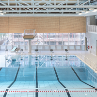Modernes Schwimmbad mit Sprungturm, Startblöcken und großen Fenstern. Helle, offene Architektur mit Sicht auf Bauarbeiten draußen., © Stuttgarter Bäder