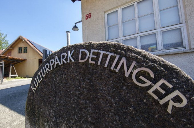 Ein Mühlstein mit der Aufschrift 'Kulturpark Dettinger' steht vor einem Gebäude mit der Hausnummer 56. Im Hintergrund ist ein weiteres Gebäude zu sehen., © PlochingenInfo Ein Mühlstein mit der Aufschrift 'Kulturpark Dettinger' steht vor einem Gebäude mit der Hausnummer 56. Im Hintergrund ist ein weiteres Gebäude zu sehen., © PlochingenInfo