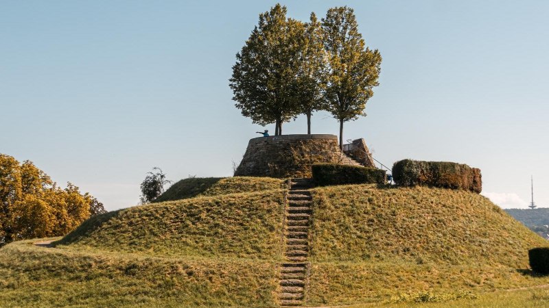 Eine grasbewachsene Erhebung mit einer Treppe f&uuml;hrt zu einer Plattform mit B&auml;umen. Der Himmel ist klar und blau., &copy; Stuttgart-Marketing GmbH, Sarah Schmid