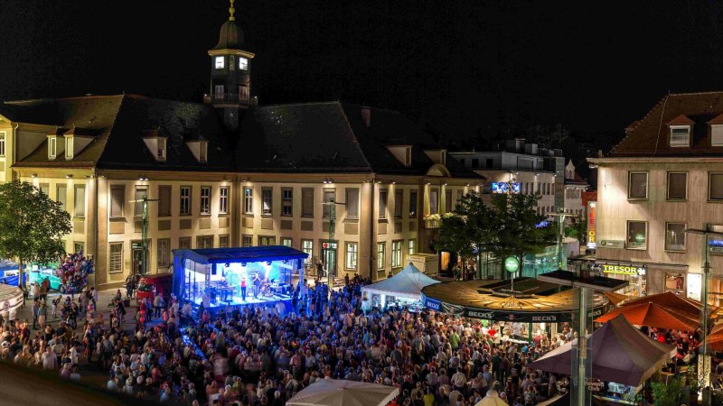 Nachtaufnahme des Göppinger Stadtfests mit beleuchteter Bühne und großer Menschenmenge vor historischen Gebäuden. Nachtaufnahme des Göppinger Stadtfests mit beleuchteter Bühne und großer Menschenmenge vor historischen Gebäuden.