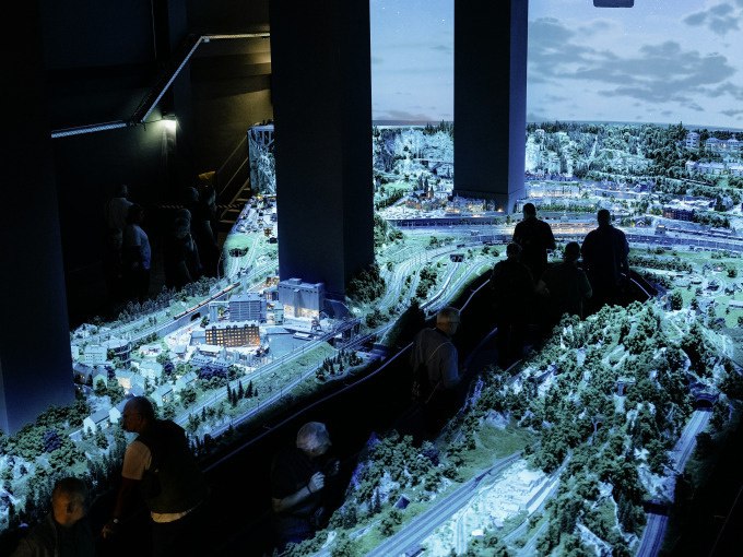 Eine gro&szlig;e Modellbahnanlage im M&auml;rklineum, beleuchtet in einer dunklen Umgebung, mit mehreren Besuchern, die die Details betrachten., &copy; M&auml;rklin Spielwaren Vertriebs-GmbH