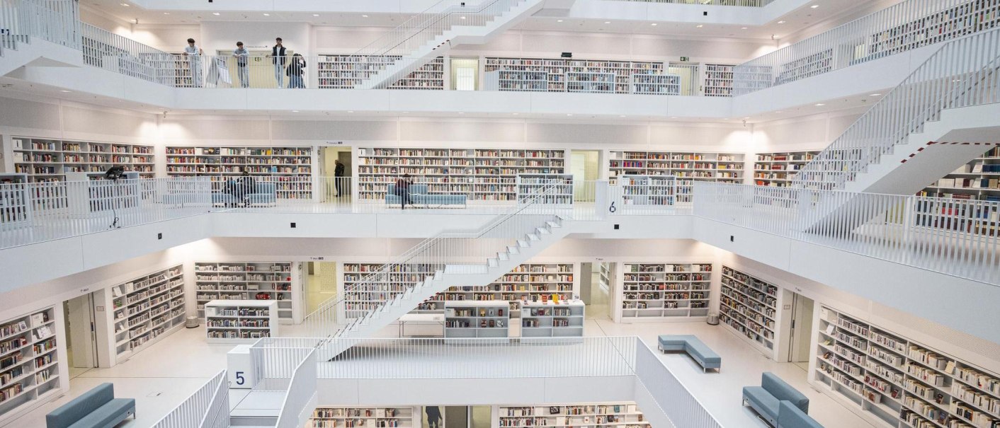 Innenansicht der Stadtbibliothek Stuttgart mit mehreren Etagen, weißen Wänden und Regalen voller Bücher. Menschen bewegen sich auf den Ebenen., © Stuttgart-Marketing GmbH, Sarah Schmid