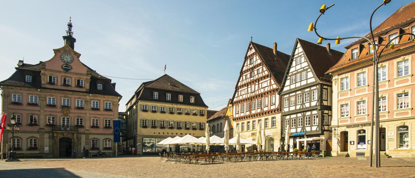 Historische Gebäude am Marktplatz in Schwäbisch Gmünd, darunter Fachwerkhäuser und das Rathaus. Sonnenschirme und leere Tische im Vordergrund., © Stuttgart-Marketing GmbH, Sarah Schmid Historische Gebäude am Marktplatz in Schwäbisch Gmünd, darunter Fachwerkhäuser und das Rathaus. Sonnenschirme und leere Tische im Vordergrund., © Stuttgart-Marketing GmbH, Sarah Schmid