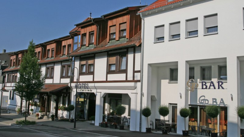 Fachwerkhotel mit moderner Fassade, Hotel Goldener Pflug. Links Bäume, rechts Barbereich mit Sitzgelegenheiten. Sonniger Tag., © Hotel & Restaurant Goldener Pflug