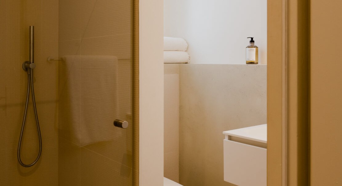 Modernes Badezimmer mit Glasdusche, Toilette und Waschbecken. Handtücher und Seifenspender sind vorhanden. Minimalistisches Design in warmen Tönen., © Peter Oliver Wolff / DAS EDITH