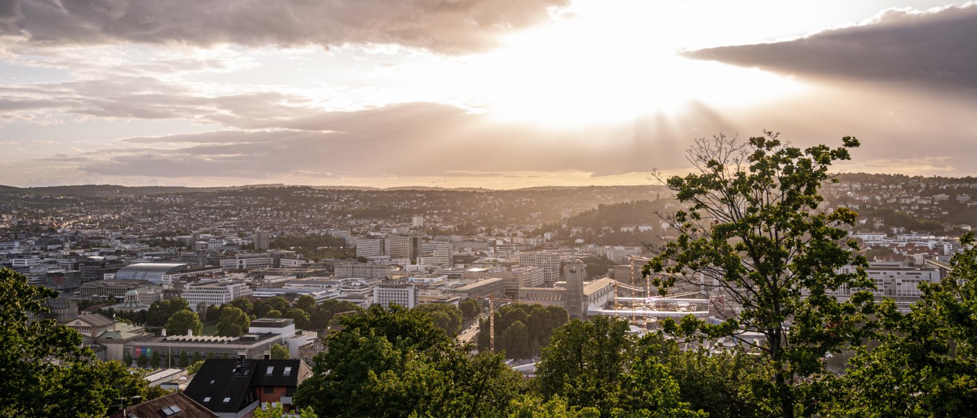 Blick von der Uhlandsh&ouml;he auf Stuttgart bei Sonnenuntergang. Die Stadt liegt unter einem dramatischen Himmel mit Sonnenstrahlen und Wolken., &copy; Christine Garcia, Urban Trickytine