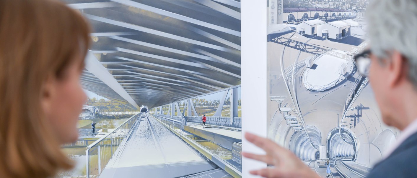 Zwei Personen betrachten detaillierte Architekturzeichnungen in einer Galerie. Die Bilder zeigen futuristische Tunnel- und Br&uuml;ckenkonstruktionen., &copy; GALERIE Z