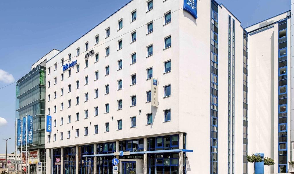 Das ibis budget Stuttgart City Nord ist ein modernes, weißes Gebäude mit blauen Akzenten und vielen Fenstern. Es liegt an einer belebten Straße., © ibis budget Stuttgart City Nord