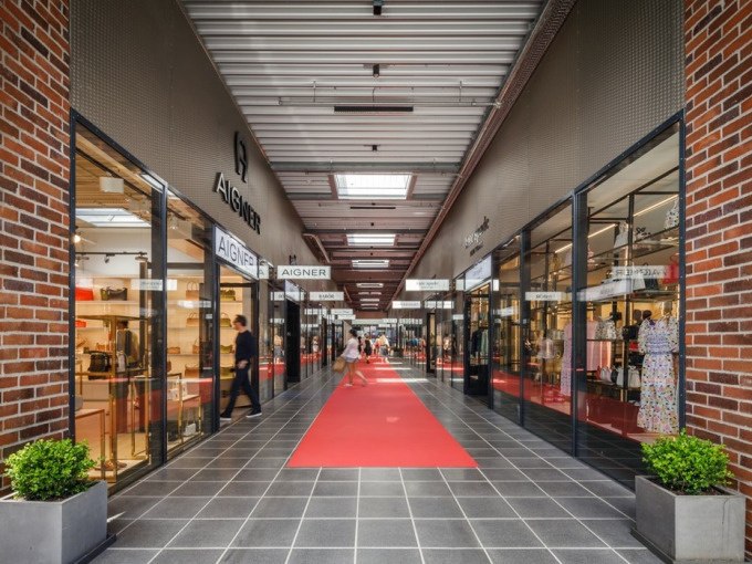 Einkaufspassage mit roten Teppichen, Gesch&auml;ften wie Aigner auf beiden Seiten und Menschen beim Einkaufen., &copy; Schlienz-Tours GmbH &amp; Co.KG