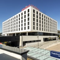 Modernes Gebäude mit Mövenpick-Logo, nahe einem Flughafen oder Messegelände. Klare Linien und große Fenster prägen die Architektur., © Mövenpick Hotel Stuttgart Messe & Congress