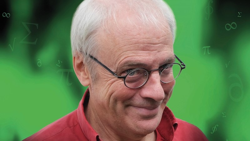 Ein Mann mit Brille und rotem Hemd l&auml;chelt vor einem gr&uuml;nen Hintergrund mit mathematischen Symbolen., &copy; Kulturhaus Schwanen