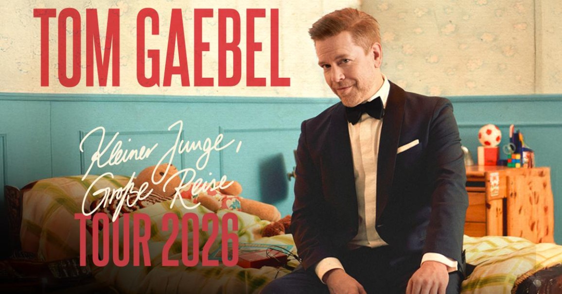 Ein Mann im Anzug sitzt auf einem Bett in einem Kinderzimmer. Text: Tom Gaebel - Kleiner Junge, große Reise - Tour 2026., © TomGaebel Ein Mann im Anzug sitzt auf einem Bett in einem Kinderzimmer. Text: Tom Gaebel - Kleiner Junge, große Reise - Tour 2026., © TomGaebel