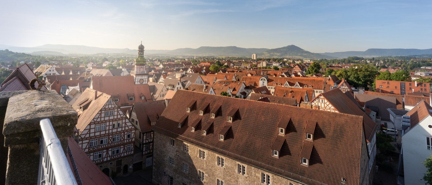 Panoramablick über Kirchheim unter Teck mit roten Dächern, Fachwerkhäusern und einem Kirchturm. Im Hintergrund sind Hügel und blauer Himmel zu sehen., © Stuttgart-Marketing GmbH, Martina Denker