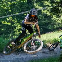 Zwei Mountainbiker mit Helmen fahren auf einem Waldweg im Adventure Bikepark Bad Wildbad. Einer springt, während der andere folgt., © Adventure Sports GmbH