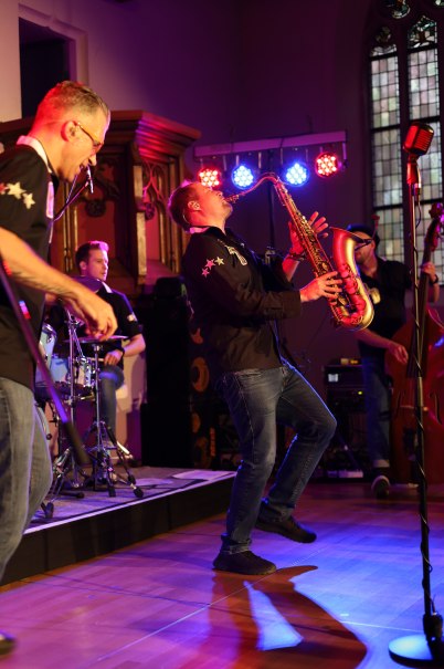 Ein Saxophonspieler performt leidenschaftlich auf einer Bühne, begleitet von einer Band mit Schlagzeug und Kontrabass, in stimmungsvoller Beleuchtung., © Stadt Nürtingen Ein Saxophonspieler performt leidenschaftlich auf einer Bühne, begleitet von einer Band mit Schlagzeug und Kontrabass, in stimmungsvoller Beleuchtung., © Stadt Nürtingen