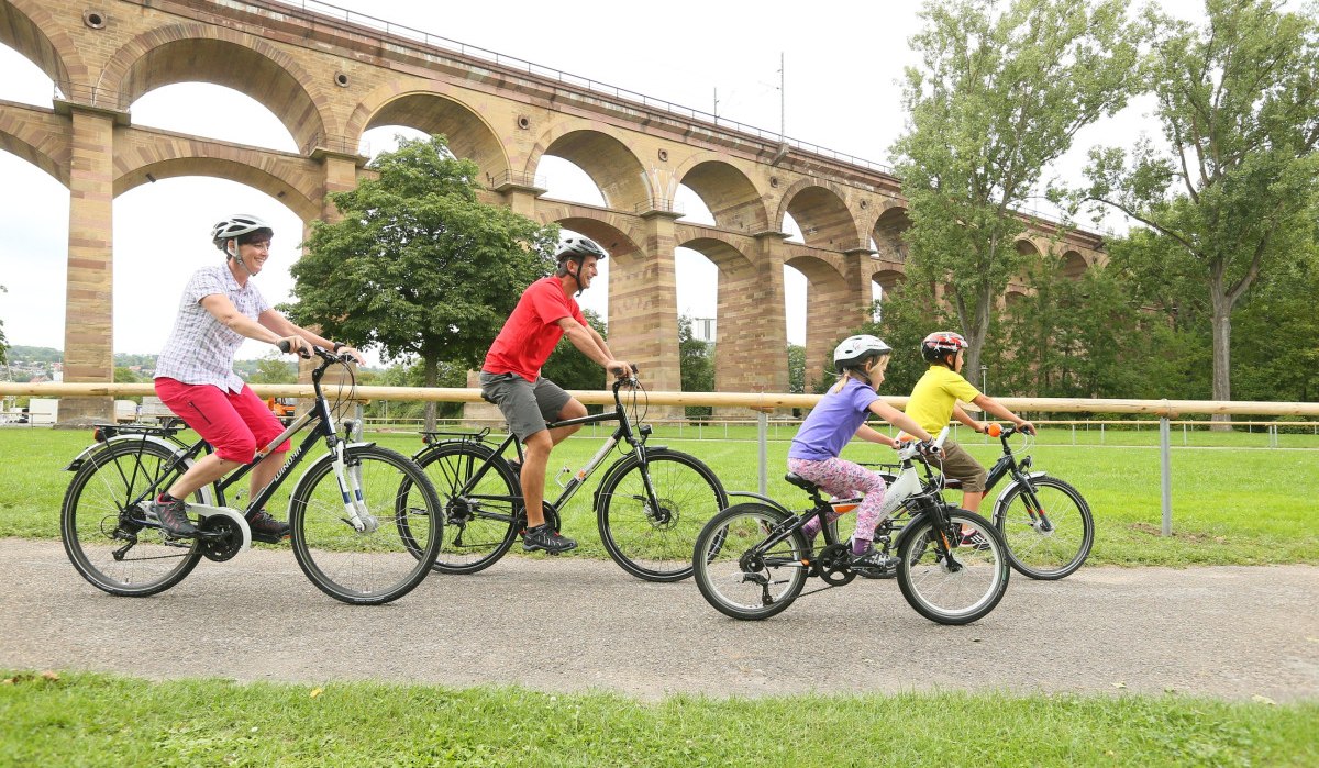Eine Familie fährt mit Fahrrädern auf einem Weg vor dem Bietigheimer Viadukt. Im Hintergrund sind Bäume und das Viadukt zu sehen., © Land der 1000 Hügel - Kraichgau-Stromberg Eine Familie fährt mit Fahrrädern auf einem Weg vor dem Bietigheimer Viadukt. Im Hintergrund sind Bäume und das Viadukt zu sehen., © Land der 1000 Hügel - Kraichgau-Stromberg