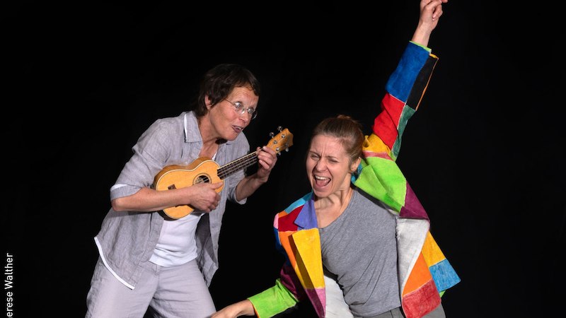 Zwei Personen auf einer Bühne, eine spielt Ukulele, die andere trägt eine bunte Jacke und hebt den Arm., © Stadt Kornwestheim Kulturmanagement Zwei Personen auf einer Bühne, eine spielt Ukulele, die andere trägt eine bunte Jacke und hebt den Arm., © Stadt Kornwestheim Kulturmanagement