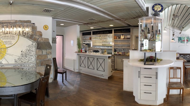 Rustikales Restaurant mit Holzmöbeln, Bar und dekorativer Wand mit "Sonnen-Besen"-Motiv. Gemütliche Atmosphäre mit Kronleuchter und Weinregal., © Weingut Zaiß Rustikales Restaurant mit Holzmöbeln, Bar und dekorativer Wand mit "Sonnen-Besen"-Motiv. Gemütliche Atmosphäre mit Kronleuchter und Weinregal., © Weingut Zaiß
