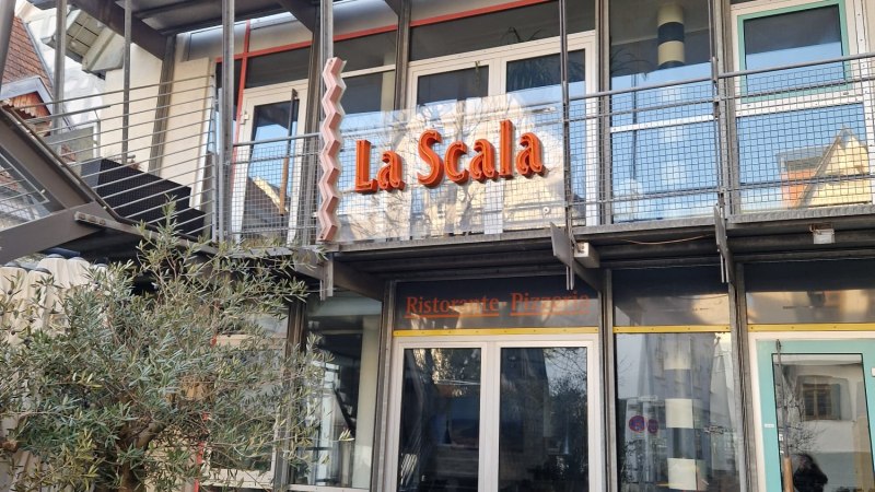 Das Bild zeigt die Fassade eines Restaurants namens La Scala mit moderner Architektur und einem Olivenbaum im Vordergrund., &copy; StadtNuertingen
