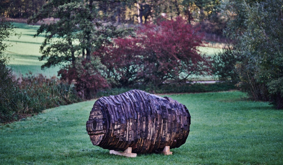 Eine Holzskulptur in Form eines Fasses steht auf einer grünen Wiese. Im Hintergrund sind Bäume und Sträucher zu sehen., © Natur.Nah. Schönbuch & Heckengäu Eine Holzskulptur in Form eines Fasses steht auf einer grünen Wiese. Im Hintergrund sind Bäume und Sträucher zu sehen., © Natur.Nah. Schönbuch & Heckengäu