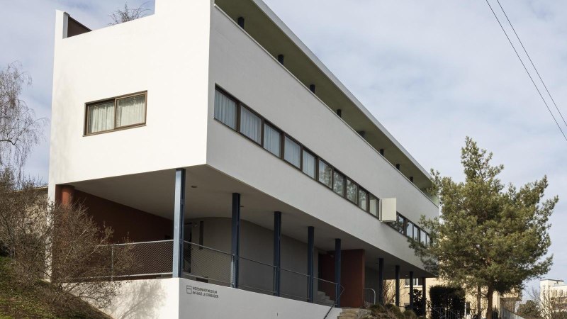 Modernes Gebäude mit weißer Fassade und großen Fenstern, umgeben von Bäumen und einem Plakatständer., © Stuttgart Marketing GmbH, Sarah Schmid Modernes Gebäude mit weißer Fassade und großen Fenstern, umgeben von Bäumen und einem Plakatständer., © Stuttgart Marketing GmbH, Sarah Schmid