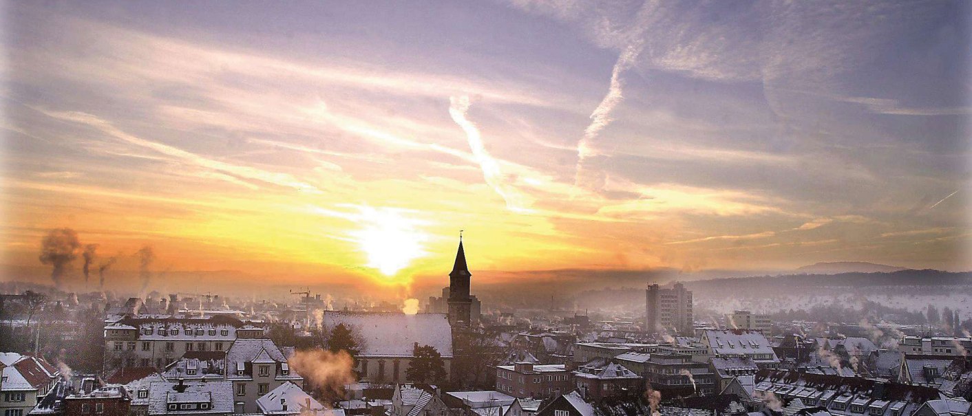 Göppingen im Winter: Schneebedeckte Dächer und Kirchturm bei Sonnenaufgang, mit rauchenden Schornsteinen und bewölktem Himmel., © Stuttgart-Marketing GmbH Göppingen im Winter: Schneebedeckte Dächer und Kirchturm bei Sonnenaufgang, mit rauchenden Schornsteinen und bewölktem Himmel., © Stuttgart-Marketing GmbH