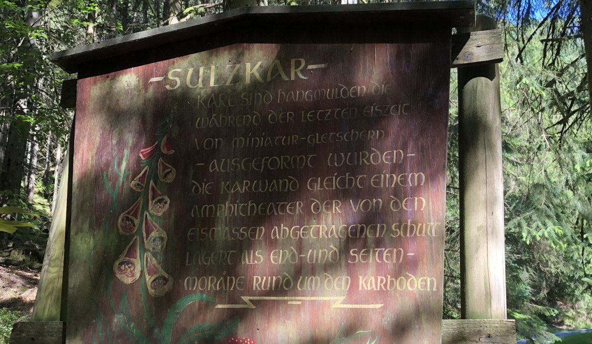 Ein Holzschild im Wald mit der Aufschrift 'Sulzkar' und Informationen über die geologische Formation. Umgeben von Bäumen und Sonnenlicht., © Nördlicher Schwarzwald Ein Holzschild im Wald mit der Aufschrift 'Sulzkar' und Informationen über die geologische Formation. Umgeben von Bäumen und Sonnenlicht., © Nördlicher Schwarzwald