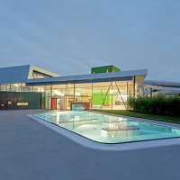 Modernes Schwimmbad mit beleuchtetem Außenpool und Glasfassade bei Dämmerung., © David Matthiessen Fotografie