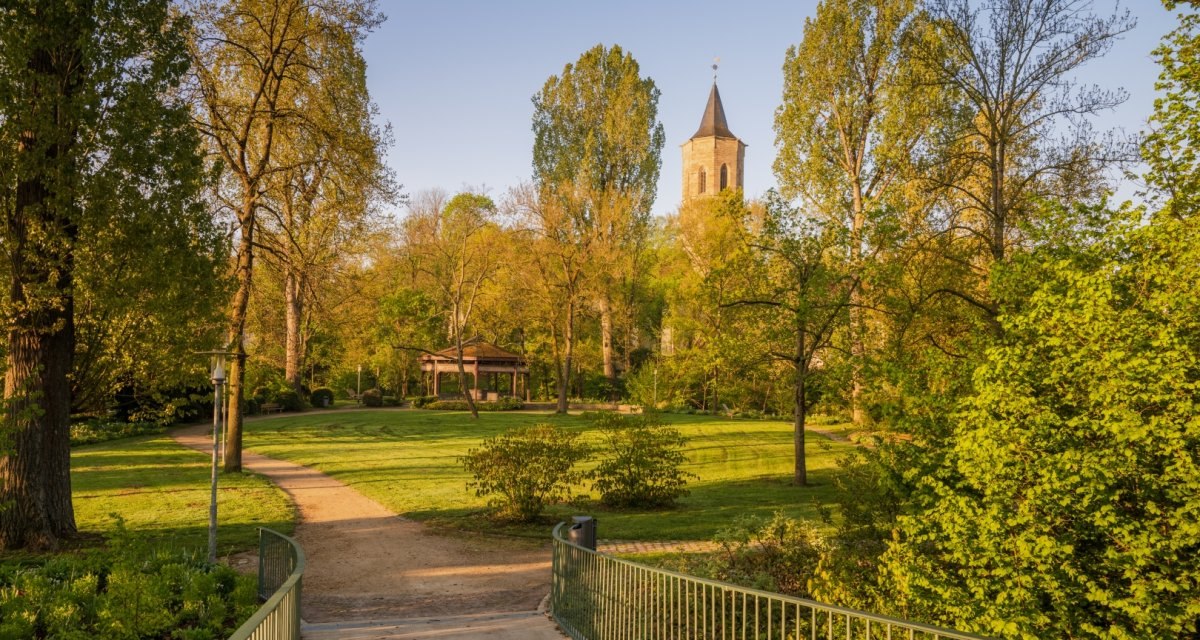 Ein grüner Park mit einem Weg, der zu einem Pavillon führt. Im Hintergrund ist ein Kirchturm zu sehen, umgeben von Bäumen im Sonnenlicht., © Remstal Tourismus e.V. Ein grüner Park mit einem Weg, der zu einem Pavillon führt. Im Hintergrund ist ein Kirchturm zu sehen, umgeben von Bäumen im Sonnenlicht., © Remstal Tourismus e.V.