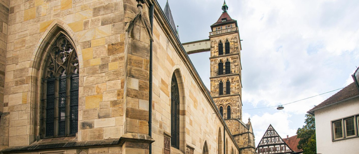 Die Stadtkirche St. Dionys in Esslingen zeigt gotische Architektur mit markanten Fenstern und einem hohen Turm. Im Hintergrund sind Fachwerkhäuser zu sehen., © Stuttgart-Marketing GmbH, Sarah Schmid