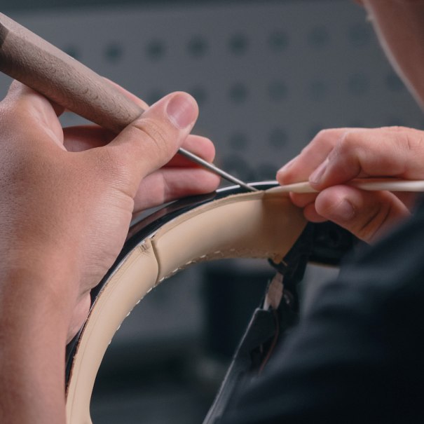 Ein Handwerker bearbeitet sorgfältig ein Lenkrad mit speziellen Werkzeugen. Die Detailarbeit zeigt Präzision und Handwerkskunst., © Mercedes-Benz AG