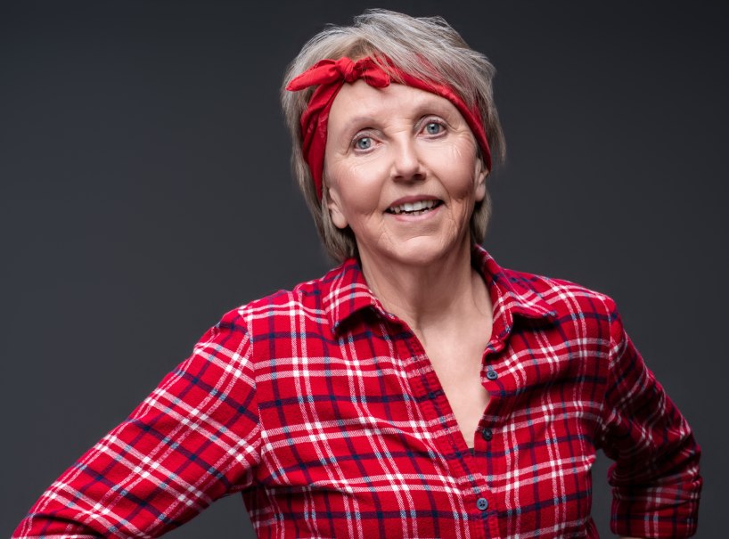 Eine Frau mit rotem Stirnband und kariertem Hemd l&auml;chelt in die Kamera. Der Hintergrund ist dunkelgrau., &copy; jean m. laffitau