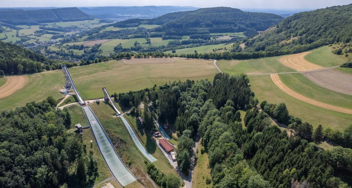 Luftaufnahme der Degenfelder Skisprungschanzen in einer gr&uuml;nen, h&uuml;geligen Landschaft mit W&auml;ldern und Feldern., &copy; Foto Thomas Zehnder