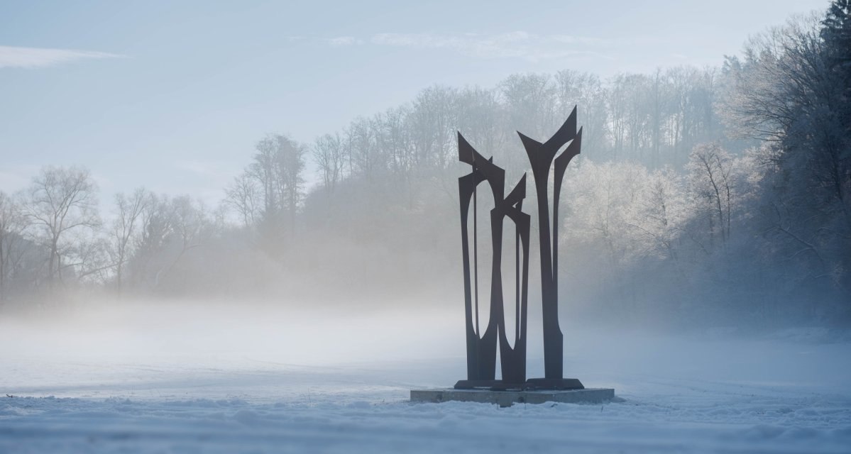 Skulptur "Les Arbres" von Dominique Coutelle in einer nebligen, verschneiten Landschaft mit B&auml;umen im Hintergrund., &copy; Natur.Nah. Sch&ouml;nbuch & Heckeng&auml;u