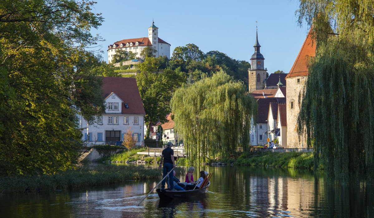 Ein Stocherkahn auf einem Fluss in Vaihingen an der Enz, umgeben von historischen Gebäuden und Bäumen. Im Hintergrund ist eine Burg zu sehen., © Stadt Vaihingen an der Enz Ein Stocherkahn auf einem Fluss in Vaihingen an der Enz, umgeben von historischen Gebäuden und Bäumen. Im Hintergrund ist eine Burg zu sehen., © Stadt Vaihingen an der Enz