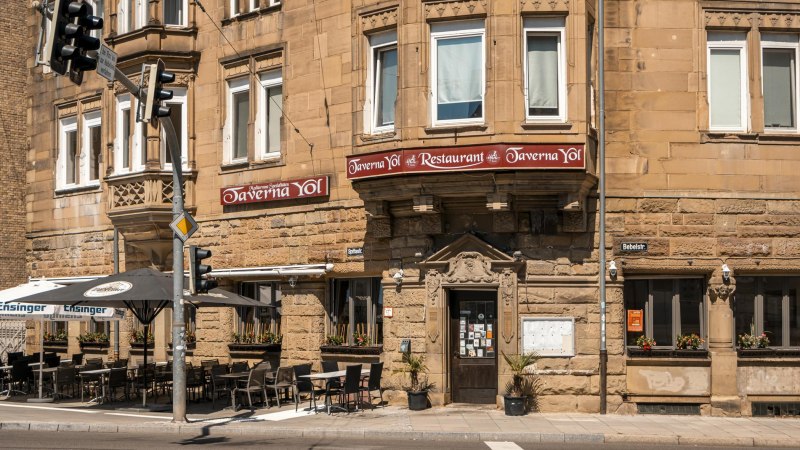 Historisches Gebäude mit Restaurant Taverna Yol, Sitzplätze im Freien, Straßenschilder und Ampeln. Sonniger Tag, Blumen in Fenstern., © SMG, Sarah Schmid Historisches Gebäude mit Restaurant Taverna Yol, Sitzplätze im Freien, Straßenschilder und Ampeln. Sonniger Tag, Blumen in Fenstern., © SMG, Sarah Schmid