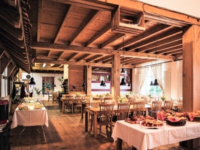 Rustikales Restaurant mit Holzbalken und gedeckten Tischen. Ein Buffet mit Speisen steht bereit. Gemütliche Atmosphäre mit Holzmöbeln., © SwabianTravel Rustikales Restaurant mit Holzbalken und gedeckten Tischen. Ein Buffet mit Speisen steht bereit. Gemütliche Atmosphäre mit Holzmöbeln., © SwabianTravel