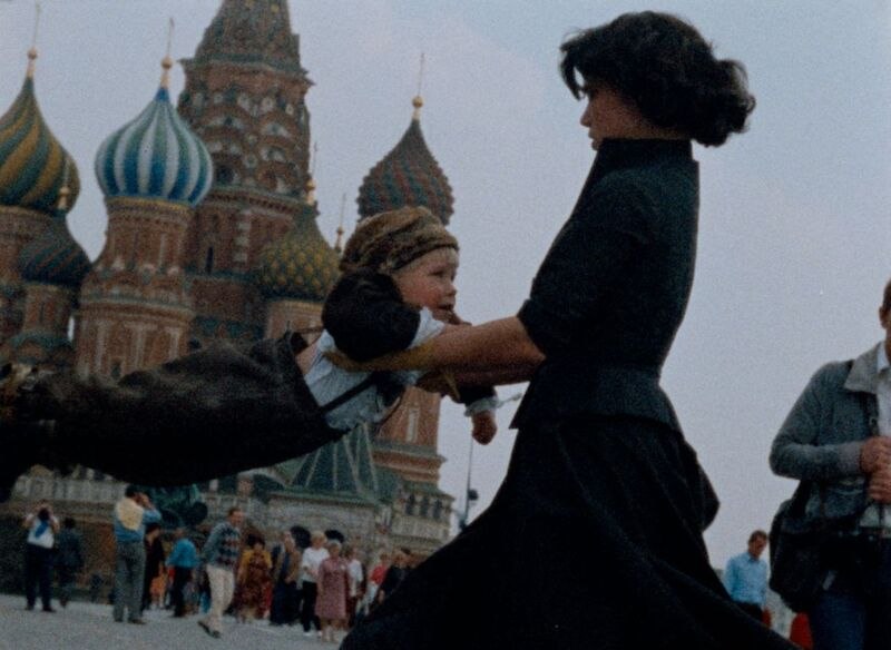 Eine Frau schwingt ein Kind vor der Basilius-Kathedrale in Moskau. Im Hintergrund sind Menschen und die bunten Türme der Kathedrale zu sehen., © Kulturhaus Schwanen Eine Frau schwingt ein Kind vor der Basilius-Kathedrale in Moskau. Im Hintergrund sind Menschen und die bunten Türme der Kathedrale zu sehen., © Kulturhaus Schwanen