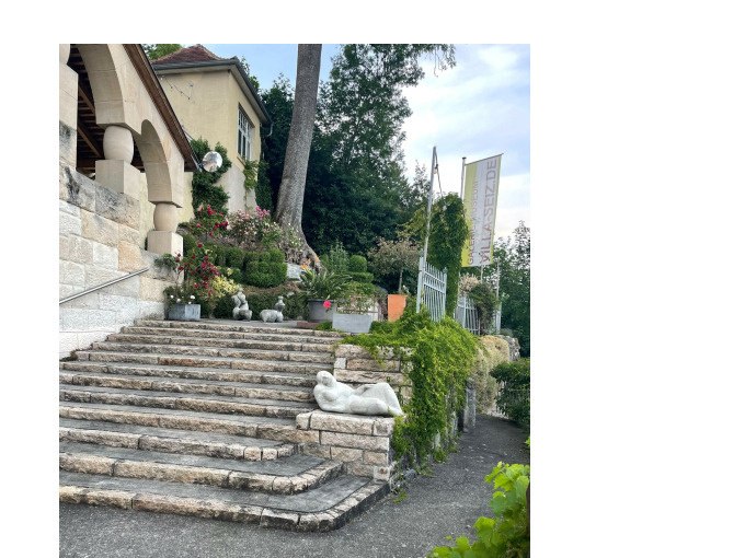 Die Steintreppe zur Villa Seiz ist von Skulpturen und üppigem Grün gesäumt. Ein Banner weist auf die Villa hin, die hoch über der Stadt thront., © Touristik und Marketing GmbH Die Steintreppe zur Villa Seiz ist von Skulpturen und üppigem Grün gesäumt. Ein Banner weist auf die Villa hin, die hoch über der Stadt thront., © Touristik und Marketing GmbH