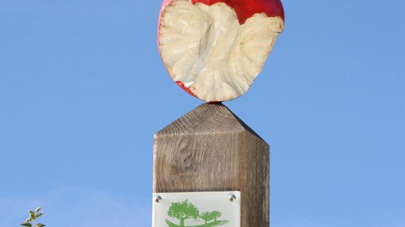 Ein hölzerner Pfosten mit einem angebissenen Apfel oben und einem Schild mit der Aufschrift 'Streuobst Erlebnis Herrenberg' vor blauem Himmel., © Natur.Nah. Schönbuch & Heckengäu Ein hölzerner Pfosten mit einem angebissenen Apfel oben und einem Schild mit der Aufschrift 'Streuobst Erlebnis Herrenberg' vor blauem Himmel., © Natur.Nah. Schönbuch & Heckengäu