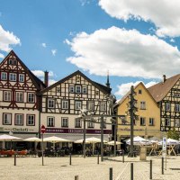 Marktplatz in Bad Urach mit malerischen Fachwerkhäusern, Cafés und Menschen bei sonnigem Wetter. Ein Radfahrer und Spaziergänger sind zu sehen., © Stuttgart-Marketing GmbH, Sarah Schmid Marktplatz in Bad Urach mit malerischen Fachwerkhäusern, Cafés und Menschen bei sonnigem Wetter. Ein Radfahrer und Spaziergänger sind zu sehen., © Stuttgart-Marketing GmbH, Sarah Schmid