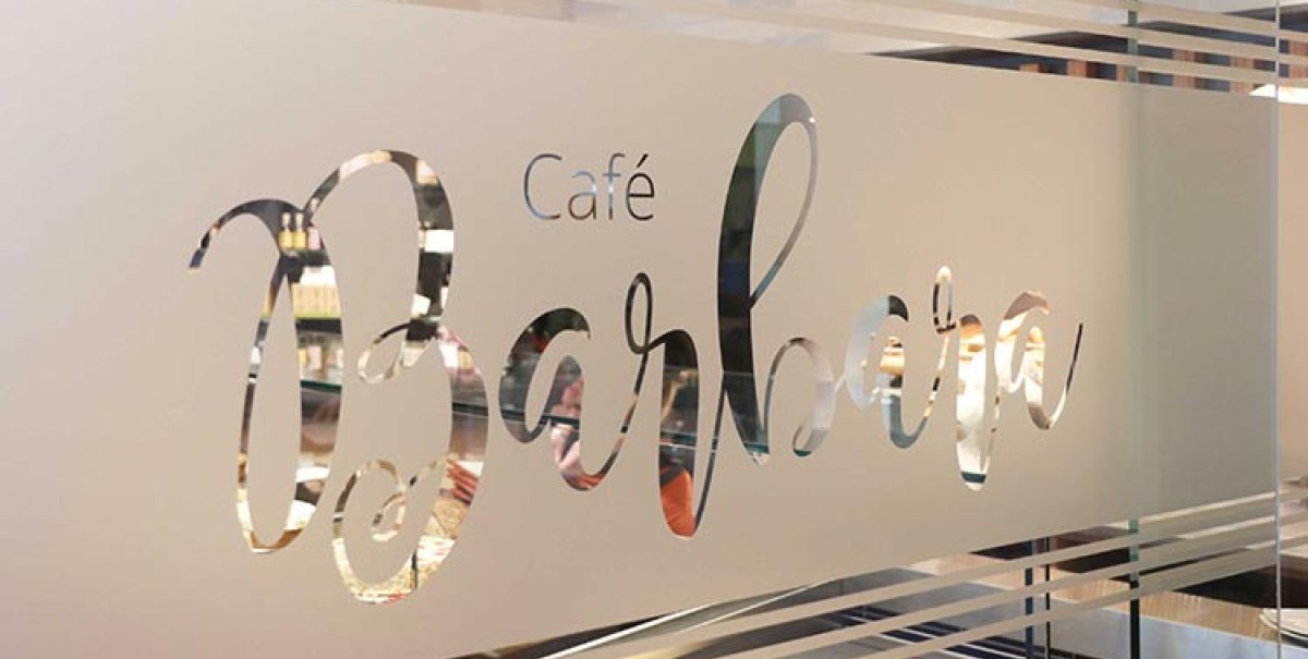 Eine Glaswand mit dem Schriftzug 'Café Barbara' in eleganter Schrift, durch die man in ein Café blicken kann., © Biosphärenhotel Graf Eberhard