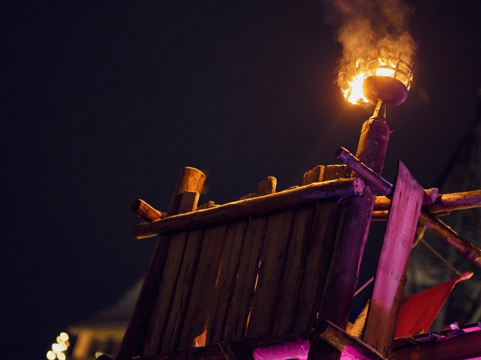 Eine mittelalterliche Holzplattform mit einer brennenden Fackel, die den Nachthimmel erleuchtet. Im Hintergrund sind Lichter zu sehen., © Esslinger Stadtmarketing &amp; Tourismus GmbH