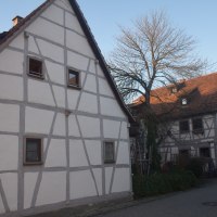 Zwei Fachwerkhäuser in einer ländlichen Straße, umgeben von kahlen Bäumen und parkenden Autos., © Land der 1000 Hügel - Kraichgau-Stromberg Zwei Fachwerkhäuser in einer ländlichen Straße, umgeben von kahlen Bäumen und parkenden Autos., © Land der 1000 Hügel - Kraichgau-Stromberg