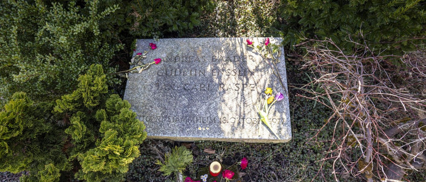 Ein Grabstein auf dem Dornhaldenfriedhof, umgeben von Pflanzen. Auf dem Stein liegen Blumen und eine Kerze steht davor., © Stuttgart-Marketing GmbH, Sarah Schmid