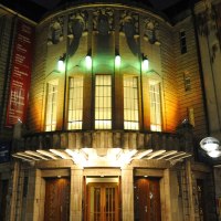 Das Alte Schauspielhaus bei Nacht, beleuchtet mit bunten Lichtern. Der Eingang ist von historischen Gebäuden umgeben., © Schauspielbühnen Stuttgart