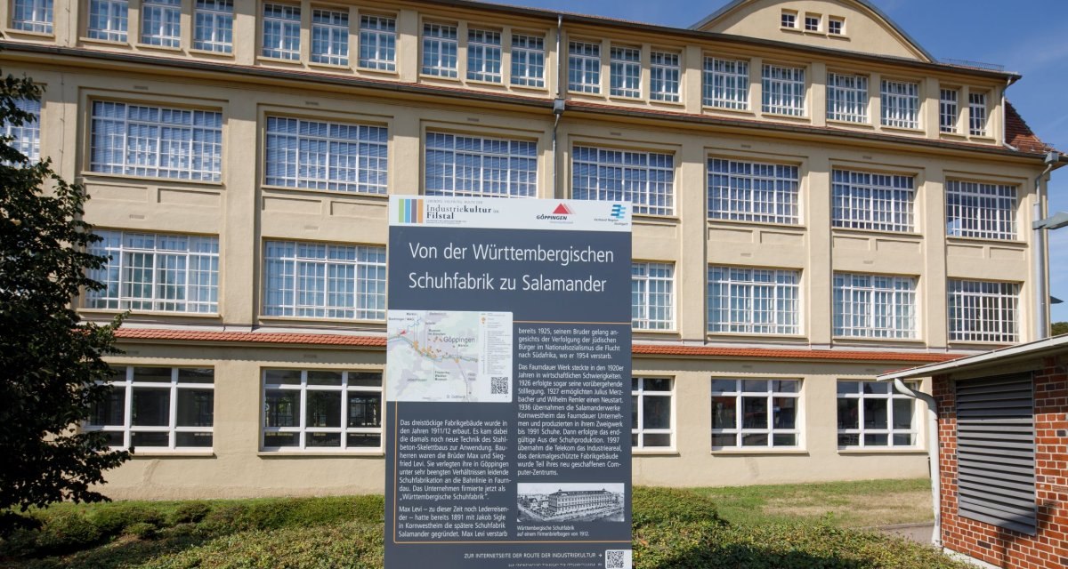 Ein historisches Gebäude mit großen Fenstern und einer Infotafel zur Geschichte der Württembergischen Schuhfabrik Salamander., © Stoppel Ein historisches Gebäude mit großen Fenstern und einer Infotafel zur Geschichte der Württembergischen Schuhfabrik Salamander., © Stoppel