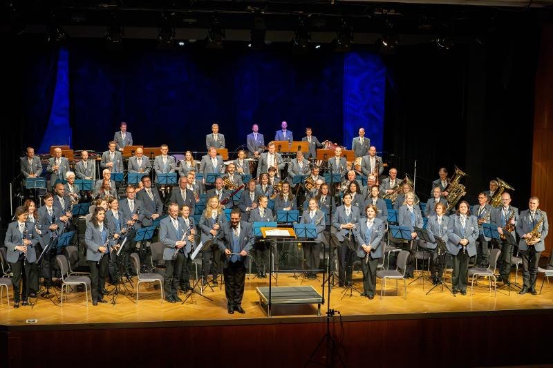 Das St&auml;dtische Blasorchester steht in blauen Uniformen auf einer B&uuml;hne, bereit f&uuml;r das Jahreskonzert. Die Musiker halten ihre Instrumente und l&auml;cheln., &copy; St&auml;dtisches Blasorchester Backnang_Foto_(c)_Moritz Lenz