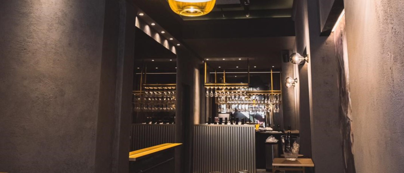 Stilvolle Bar mit modernem Design, hängenden Gläsern und eleganter Beleuchtung. Der Tresen ist zentral platziert, umgeben von dunklen Wänden., © KESSLER Sekt GmbH & Co. KG Stilvolle Bar mit modernem Design, hängenden Gläsern und eleganter Beleuchtung. Der Tresen ist zentral platziert, umgeben von dunklen Wänden., © KESSLER Sekt GmbH & Co. KG